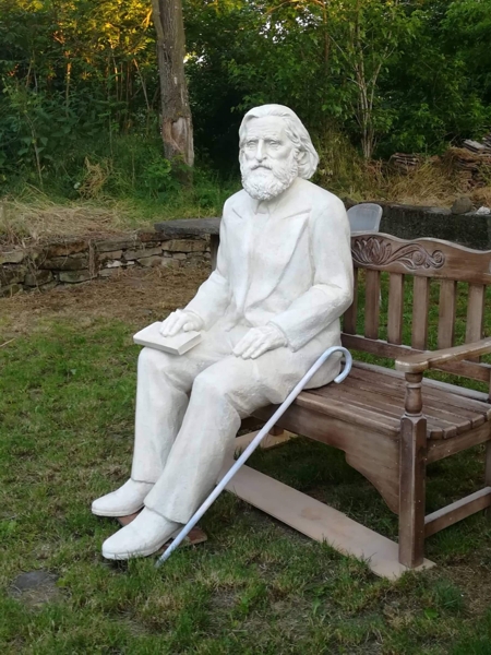 Скулптура на Учителя Петър Дънов, седнал на пейка, изглед отпред