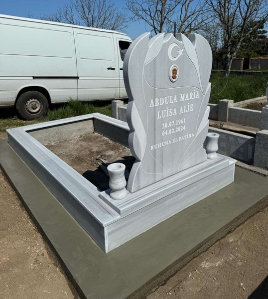 Muslim monument with crescent and star, colored elliptical porcelain photo, inscription in carved white letters, two round vases, pedestal, high tiled curb, concrete path, concrete base, view of the monument's face