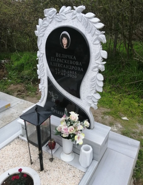 Паметник от светлосив мрамор с клонки и цветове рози, залепени черни плочи със снимка, надписи и гравирано ангелче