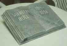 Малка книга от сив мрамор като надгробен паметник с надпис от вдълбани букви. Монтирана е в Германия.