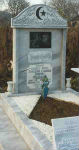 Мраморен надгробен паметник с купол с орнаменти, 2 прави колони, вграден гравиран портрет, апликации от черен гранит, надпис от релефни букви, релефна рисунка на файтон, масивен постамент, облицовка на 1 етаж и пътека, плоча с надпис в краката, 2 струговани мраморни вази, всичко от сив мрамор. паметникът е взаимстван от модел на колега