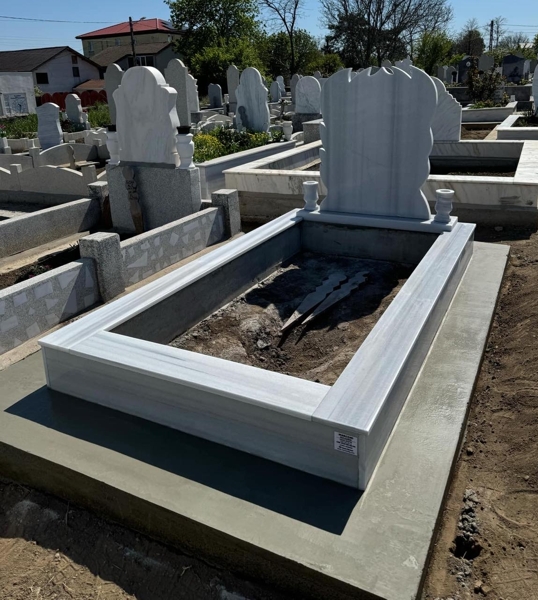 Мюсюлмански паметник с полумесец и звезда, цветна елипсовидна порцеланова снимка, надпис с вдълбани бели букви, две кръгли вази, постамент, висок облицован бордюр, бетонна пътека, бетонна основа