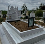 Monument musulman în formă de moschee și ornament în formă de porumbel, fotografie dreptunghiulară colorată din porțelan, inscripție cu litere albe sculptate, două vaze rotunde, piedestal, bordură masivă, bordură din gresie, alee din marmură, bază din beton.