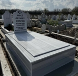 Monument musulman în formă de moschee cu semilună și stea, inscripție cu litere negre sculptate, piedestal, placă de acoperiș, bordură înaltă cu țigle, bază de beton