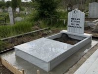 Monument musulman cu semilună și stea, inscripție cu litere negre sculptate, piedestal, bordură înaltă și masivă, placă de acoperiș la mijloc, alee de ciment, bază de beton