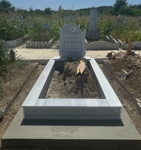 Monument musulman cu semilună și stea, inscripție cu litere albe sculptate, piedestal, bordură cu gresie, bază de beton